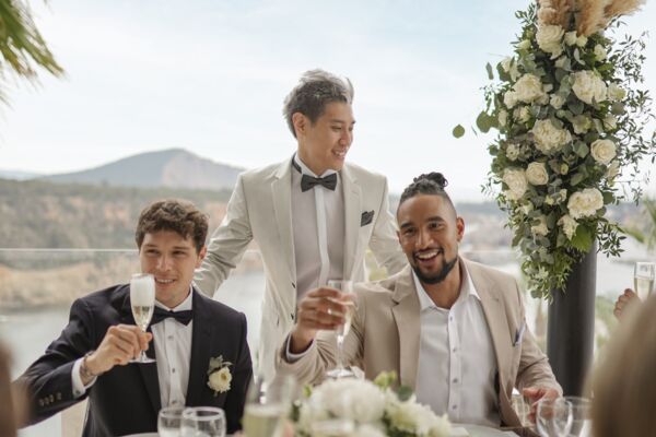 Drei Männer stoßen auf Hochzeit mit Sekt an